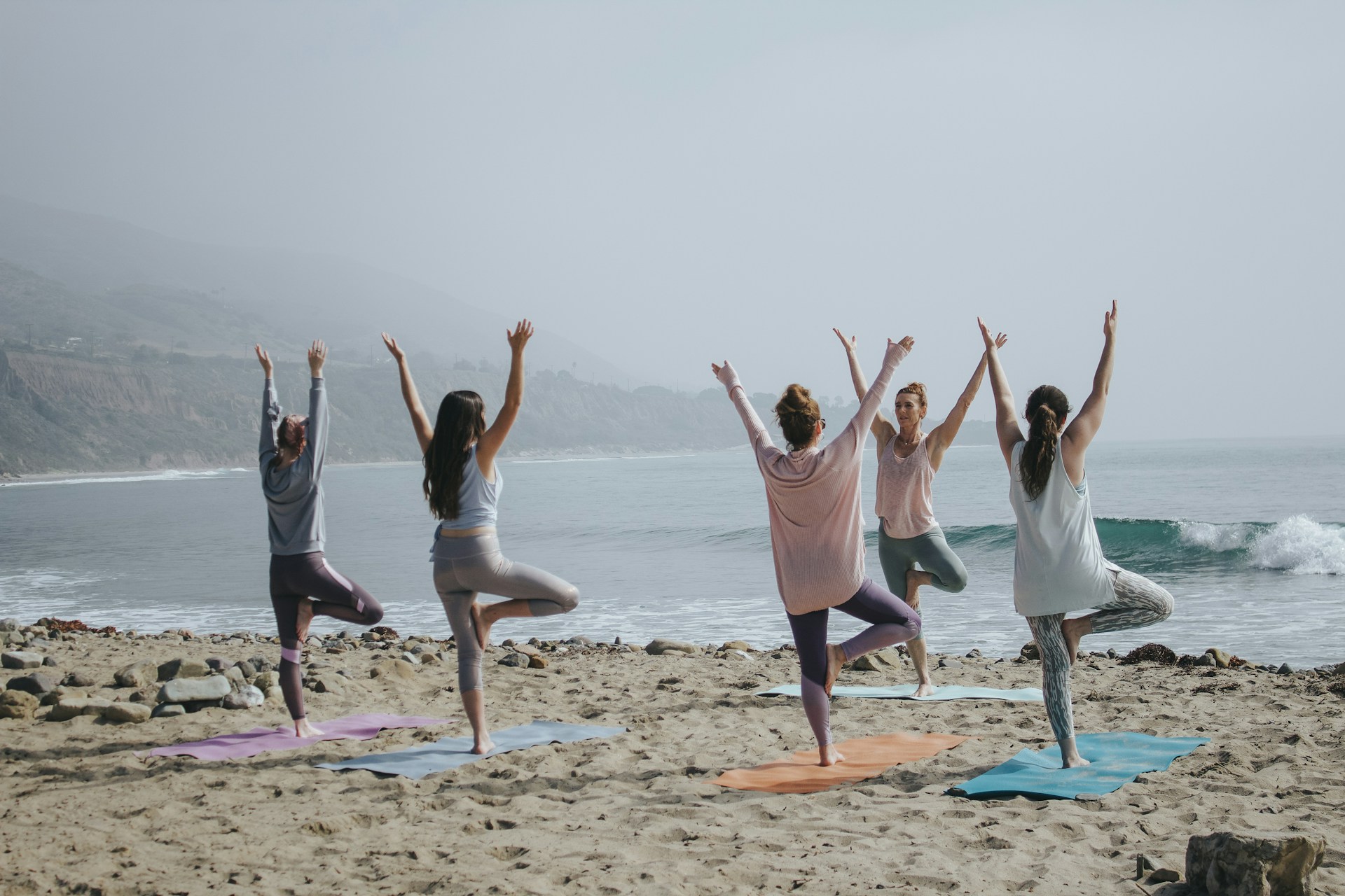 A group of women on the beach, enjoying a yoga meditation session