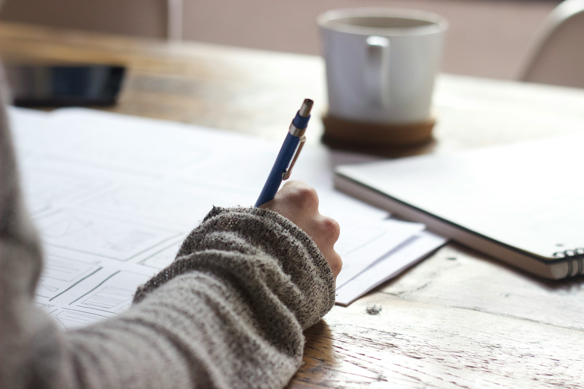 A person sitting at a desk, writing a journal to preserve their mental health